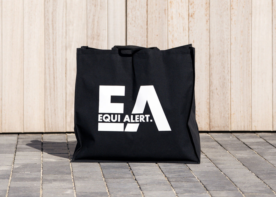 Black tote bag with 'EQUIPA ALERT' logo on a wooden background