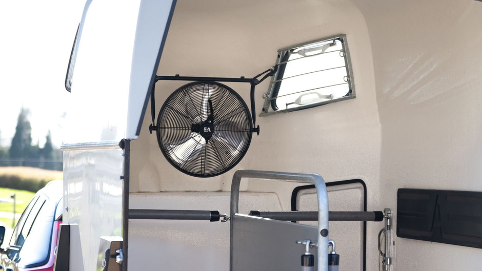 Van with a horse trailer attached, featuring a ramp and bedding inside.