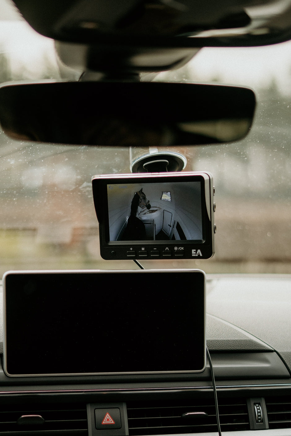 Car interior with a dashboard camera and monitor displaying a person.